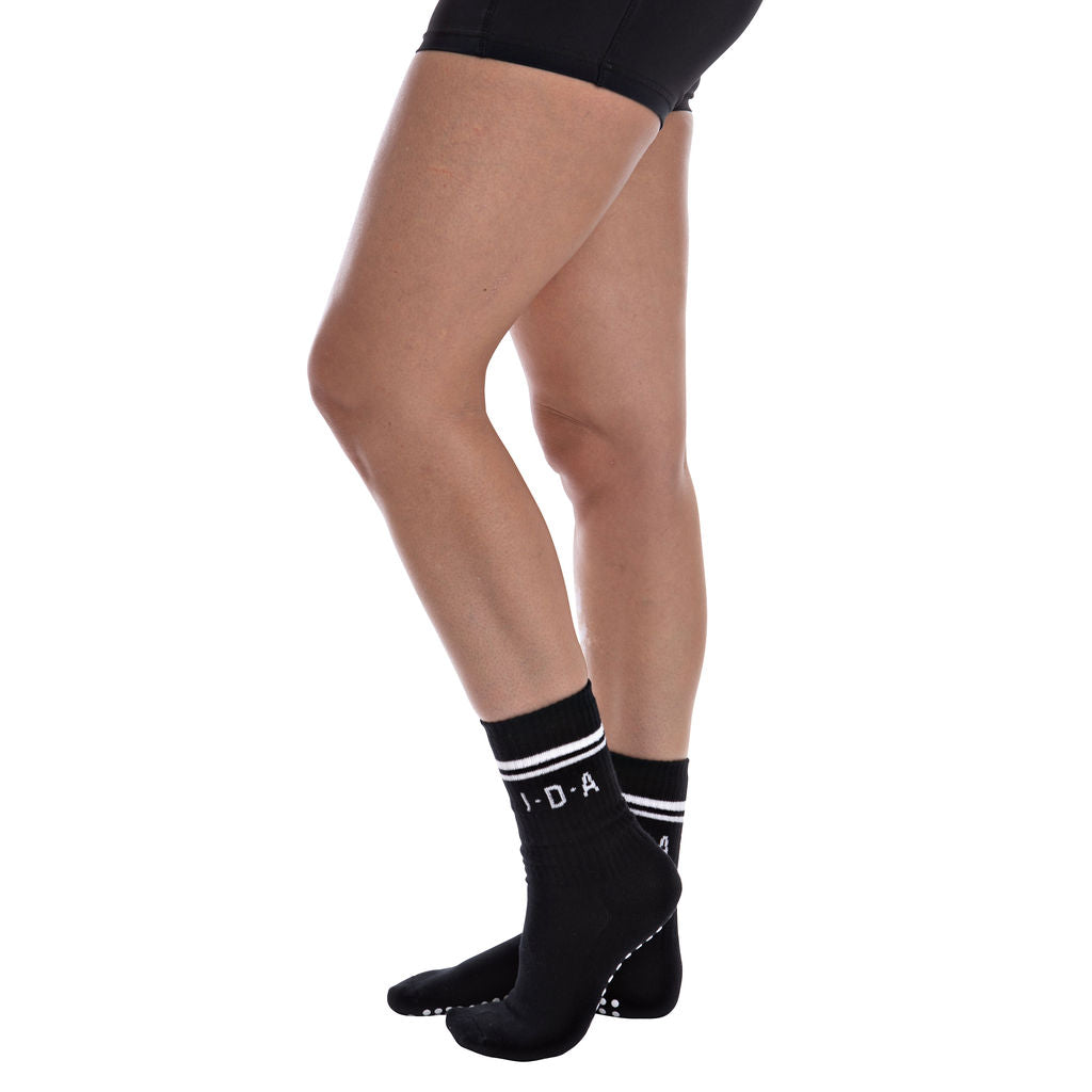 Black socks with white grip and stripes worn by a person on a white background